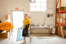 Arbeiter tragen Rahmen und T-Shirt in Siebdruckwerkstatt — Stockfoto
