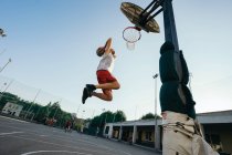 Man jumping to basketball hoop on playground — Stock Photo