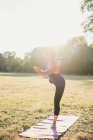 Зрелая женщина в парке, балансирует на одной ноге, в положении йоги — стоковое фото