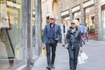 Pareja de turistas paseando con bolsas de compras en la calle de la ciudad, Siena, Toscana, Italia - foto de stock
