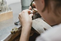 Over shoulder view of female jeweller making ring at workbench — Stock Photo