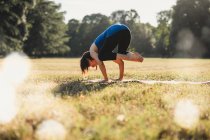 Зрелая женщина в парке, балансирует на руках, в положении йоги — стоковое фото