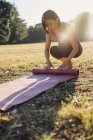 Reife Frau im Park, rollende Yogamatte — Stockfoto