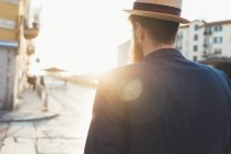 Вид сзади на человека в лодке, прогуливающегося вдоль освещенной солнцем улицы — стоковое фото