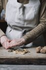 Woman chopping walnuts on chopping board, using knife, mid section — Stock Photo