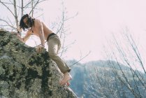 Pecho desnudo y pie desnudo macho escalada en roca - foto de stock