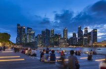 Туристи, дивлячись на горизонт міста з набережної в сутінках, Сінгапур, Південно-Східної Азії — стокове фото