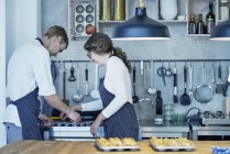 Два кухарі на кухні видаляють свіжоспечені канапки з випічки лотка — стокове фото