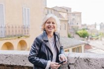 Зрелая женщина держит смартфон в городе, Сиена, Тоскана, Италия — стоковое фото