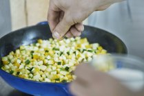 Обрізане зображення шеф-кухаря приправляє овочі на сковороді — стокове фото
