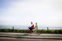 Pareja extraña turismo en bicicleta tándem, Bournemouth, Inglaterra - foto de stock