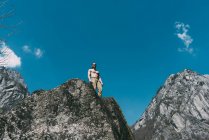 Vista basso angolo di uomo petto nudo in piedi sulla cima del masso — Foto stock