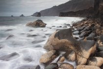 Belle vue naturelle avec des vagues se lavant sur les rochers sur la plage — Photo de stock