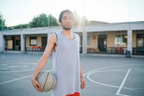 Portrait de l'homme sur le terrain de basket tenant basket regardant la caméra — Photo de stock