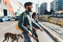 Cool couple walking dog by city canal — Stock Photo