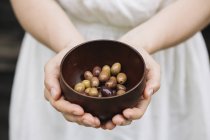 Женщина держит миску с оливками, в середине секции — стоковое фото