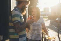 Couple raising a cocktail toast at sunlit sidewalk cafe — Stock Photo