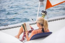 Погляд на жінку, що відпочиває на яхті, читаючи книжку 