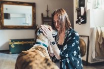 Jovem mulher acariciando seu cão no apartamento — Fotografia de Stock