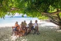 Amigos relajándose en la mesa de comedor en la playa, Koh Rang Yai, Tailandia, Asia - foto de stock