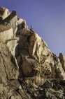 Homem montanhista olhando para fora do topo da face rochosa acidentada, Andes, Parque Nacional Nahuel Huapi, Rio Negro, Argentina — Fotografia de Stock