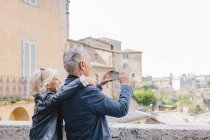 Pareja de turistas fotografiando paisaje urbano, Siena, Toscana, Italia - foto de stock