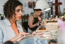 Female jeweller shaping silver metal at workbench — Stock Photo