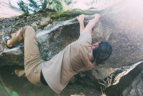 Young male boulderer climbing on edge of boulder — Stock Photo