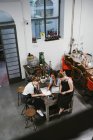 High angle view of three female jewellers looking at sketchpad at workbench meeting — Stock Photo