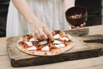 Abgeschnittenes Bild einer Frau, die Oliven auf hausgemachte Pizza legt — Stockfoto