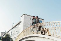 Low angle view of couple with dog looking out from footbridge — Stock Photo