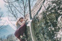 Jeune femme grimpant sur rocher — Photo de stock