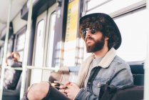 Молодий чоловік сидить на поїзді метро, використовуючи смартфон — стокове фото
