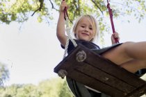 Girl on swing looking at camera in park — Stock Photo