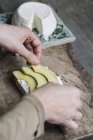 Жінка кладе скибочки авокадо на нарізаний хліб з рикоттою, крупним планом — стокове фото