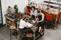 High angle view of three female jewellers having discussion at workbench meeting — Stock Photo