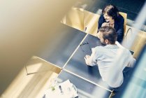 High angle window view of businesswoman and man looking over in office — Stock Photo
