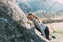 Jeune femme grimpant sur rocher — Photo de stock