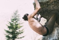 Mann mit nacktem Oberkörper klettert auf großen Findling — Stockfoto