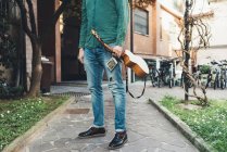 Neck down view on man standing path holding ukulele — Stock Photo