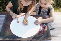 Sisters colouring out in garden — Stock Photo