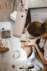 Overhead view of female jeweler using hand tool at workbench — Stock Photo