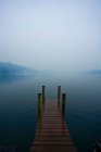 Lago Jetty com porto e montanhas em nevoeiro, itália — Fotografia de Stock