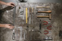 Overhead view of female jeweler laying hand tools at workbench — Stock Photo