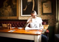 Странный человек, читающий газеты в баре и ресторане, Борнмут, Англия — стоковое фото