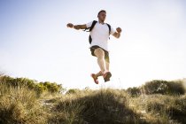 Young man jumping mid air from sand dunes — Stock Photo