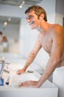 Усміхнений чоловік голиться у ванній — стокове фото