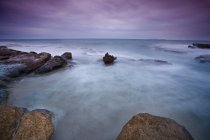 Time lapse vista de las olas en la playa rocosa - foto de stock