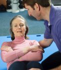 Formateur aidant femme plus âgée exercice — Photo de stock