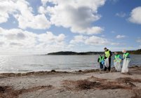 Pai e filhos limpeza praia — Fotografia de Stock